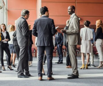 Group of professionals networking and conversing at a business event, symbolizing in-person networking opportunities for commercial insurance lead generation